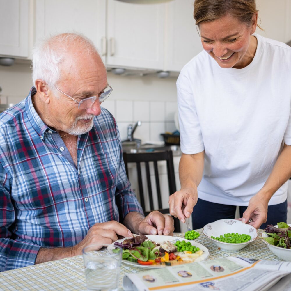 äldre man serveras näringsrik mat av vård och omsorgspersonal 